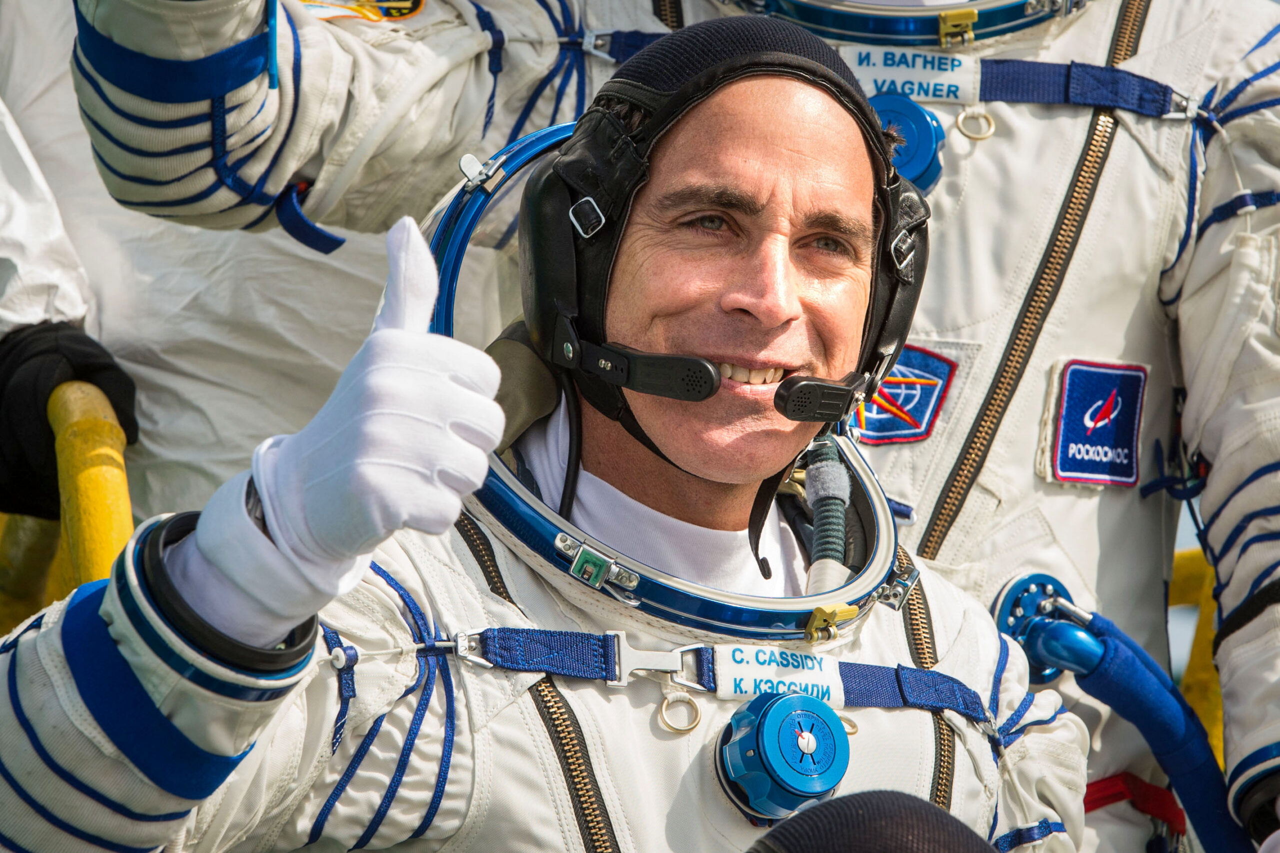 Expedition 63 Commander Chris Cassidy giving a thumbs up while wearing a Russian Sokol pressure suit and communications cap, signifying mission success and the spirit of international cooperation during the Soyuz MS‑16 mission.